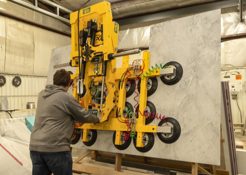   
Operator handling stone slabs in a factory using professional lifting equipment.