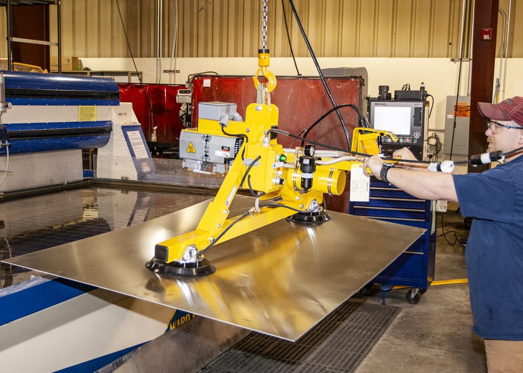 Operator lifting metal sheets using industrial vacuum lifting equipment.